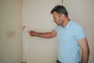 a man in a blue shirt is painting a wall