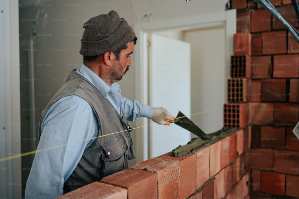 um homem está trabalhando em uma parede de tijolos