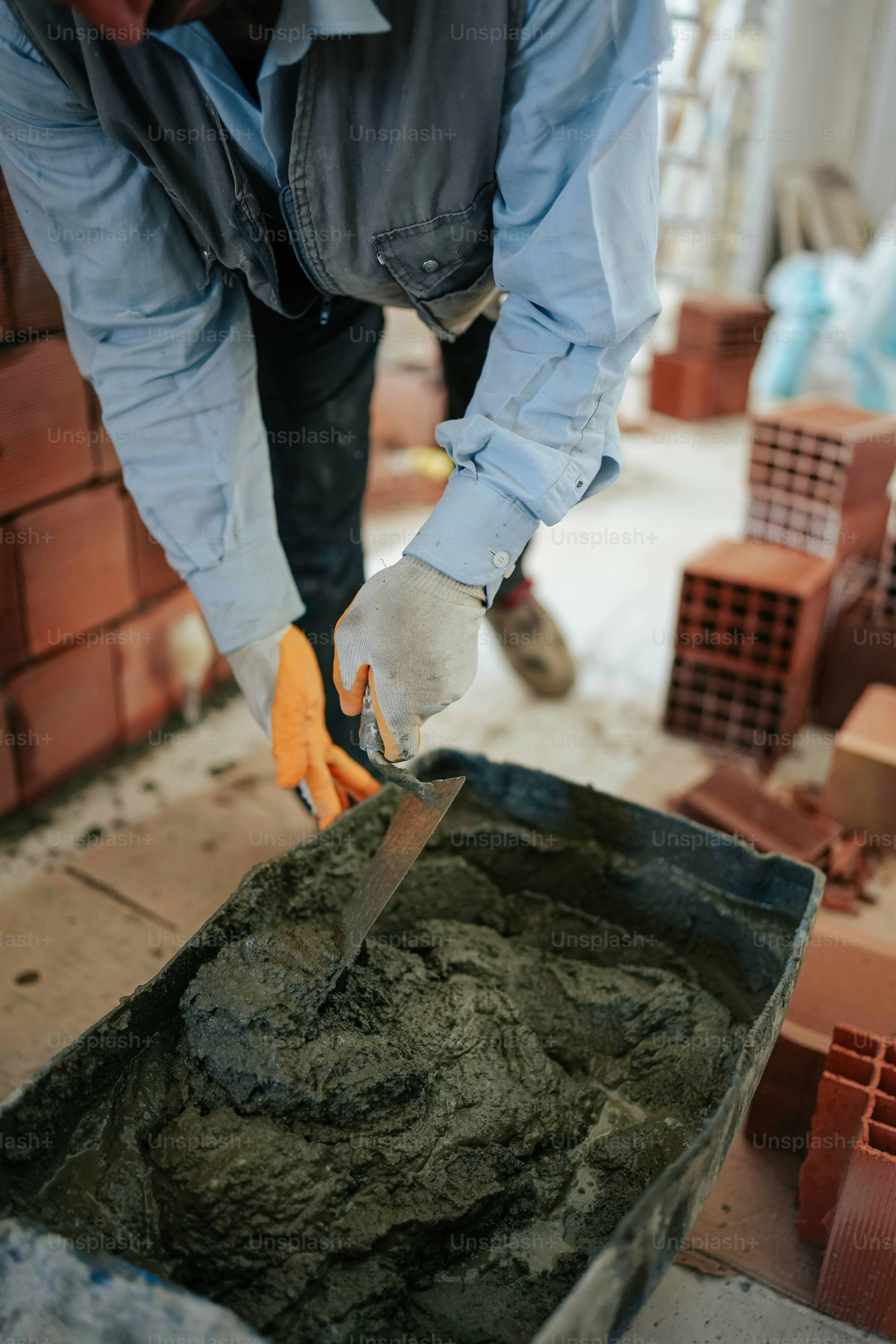 Ein Mann in einem blauen Hemd und einem Paar orangefarbener Handschuhe