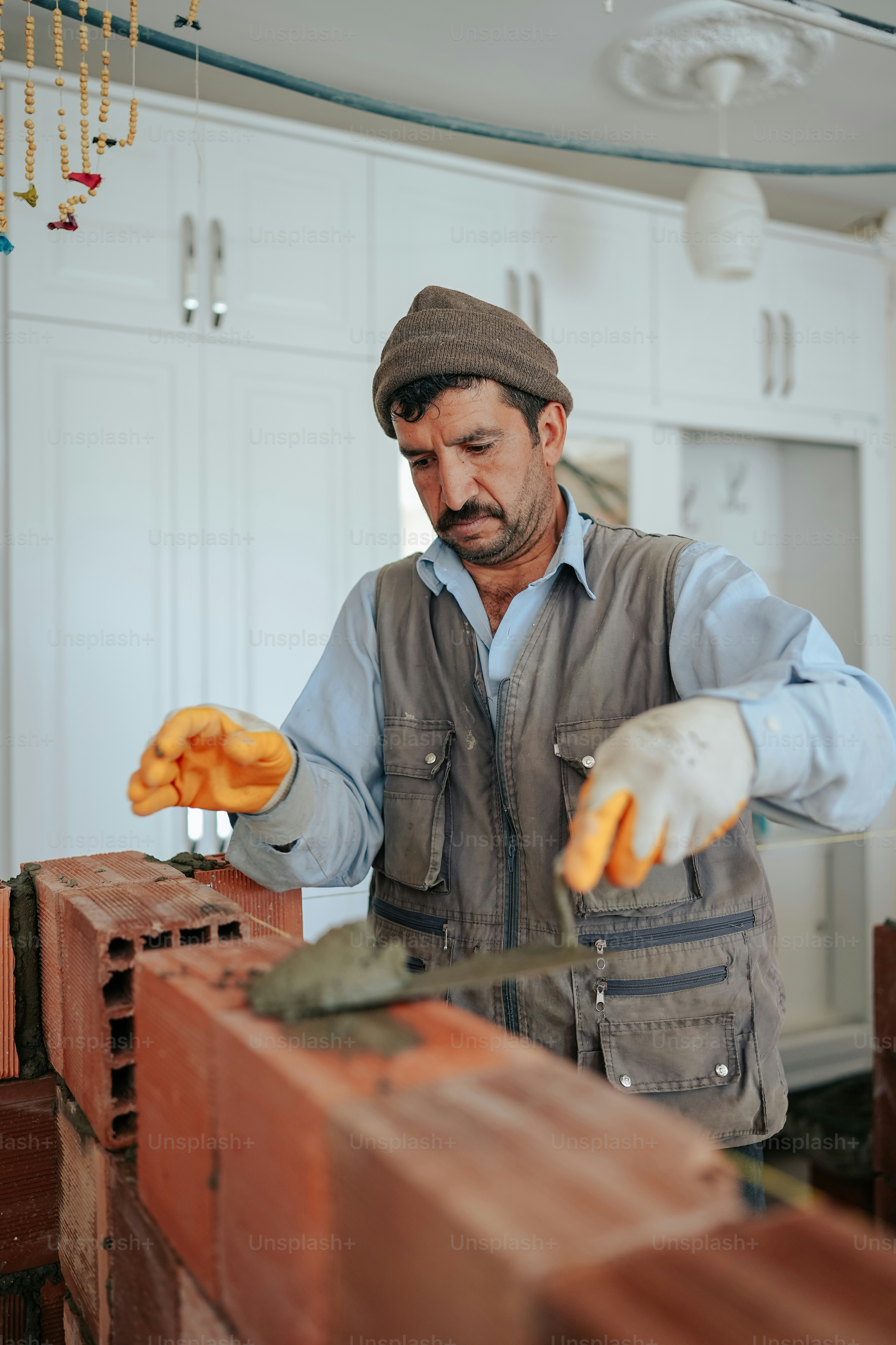 Ein Mann mit Hut und Weste steckt etwas in eine Ziegelkiste