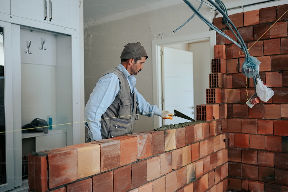 Un homme travaille sur un mur de briques