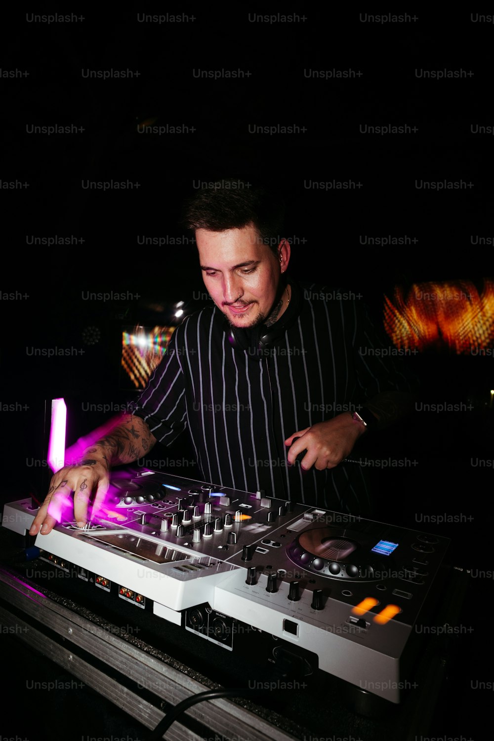 Un hombre con una camisa a rayas blancas y negras mezclando música