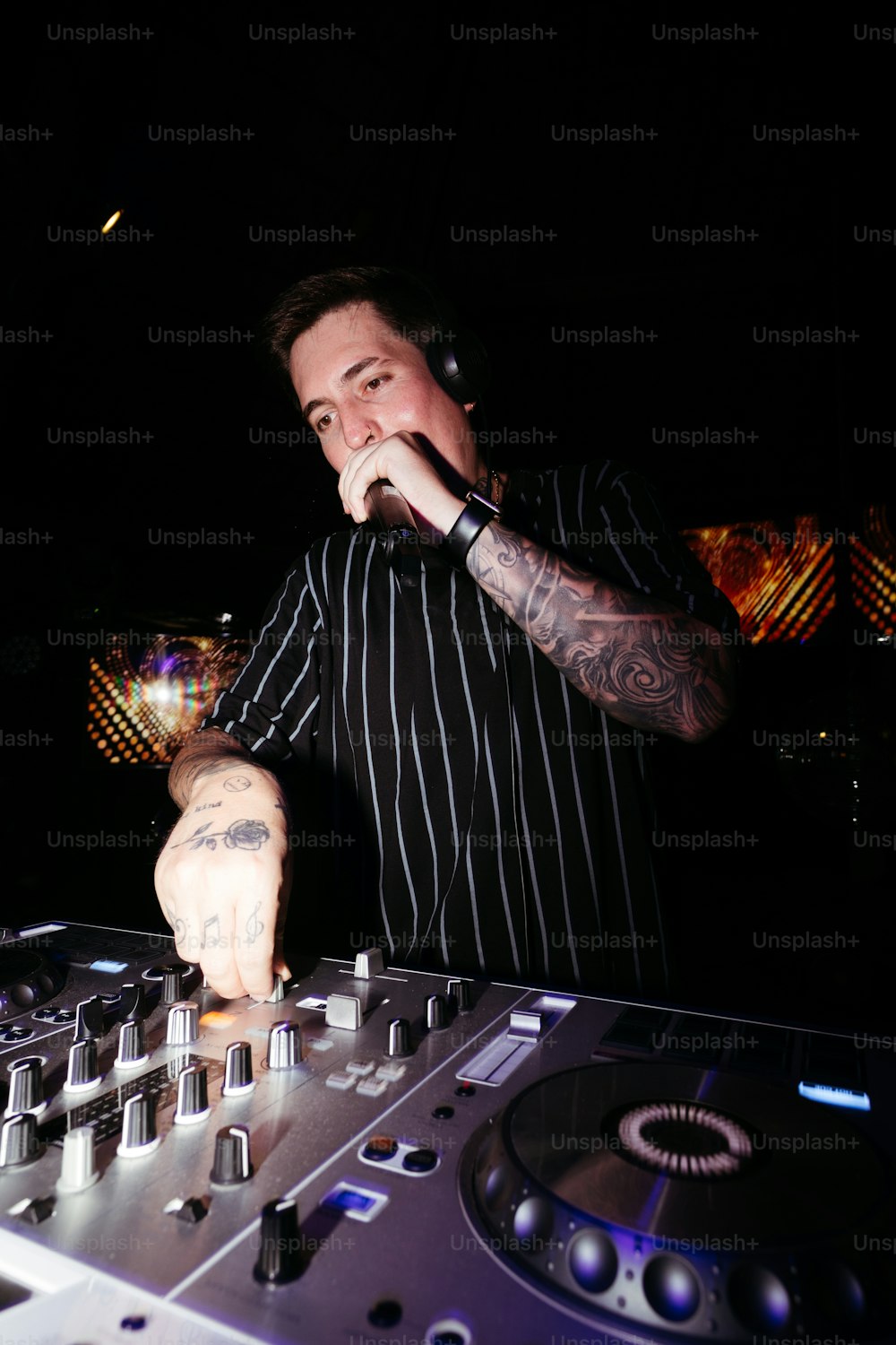 흑백 줄무늬 셔츠를 입은 남자가 DJ 세트를 연주하고 있다