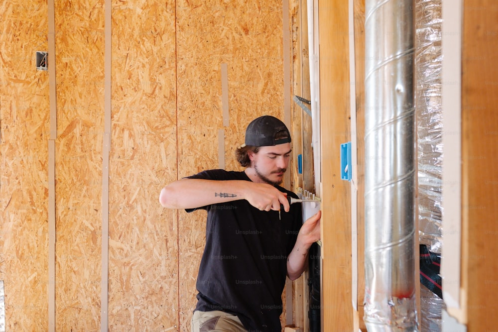 a man in a black shirt and a black hat working on a wall