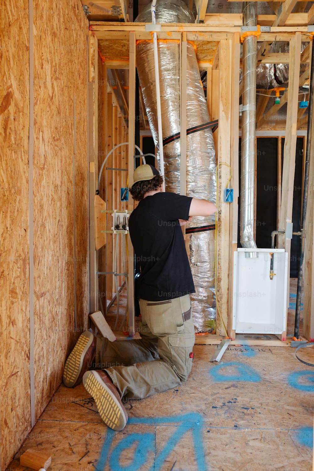 a man working on a wall in a house under construction