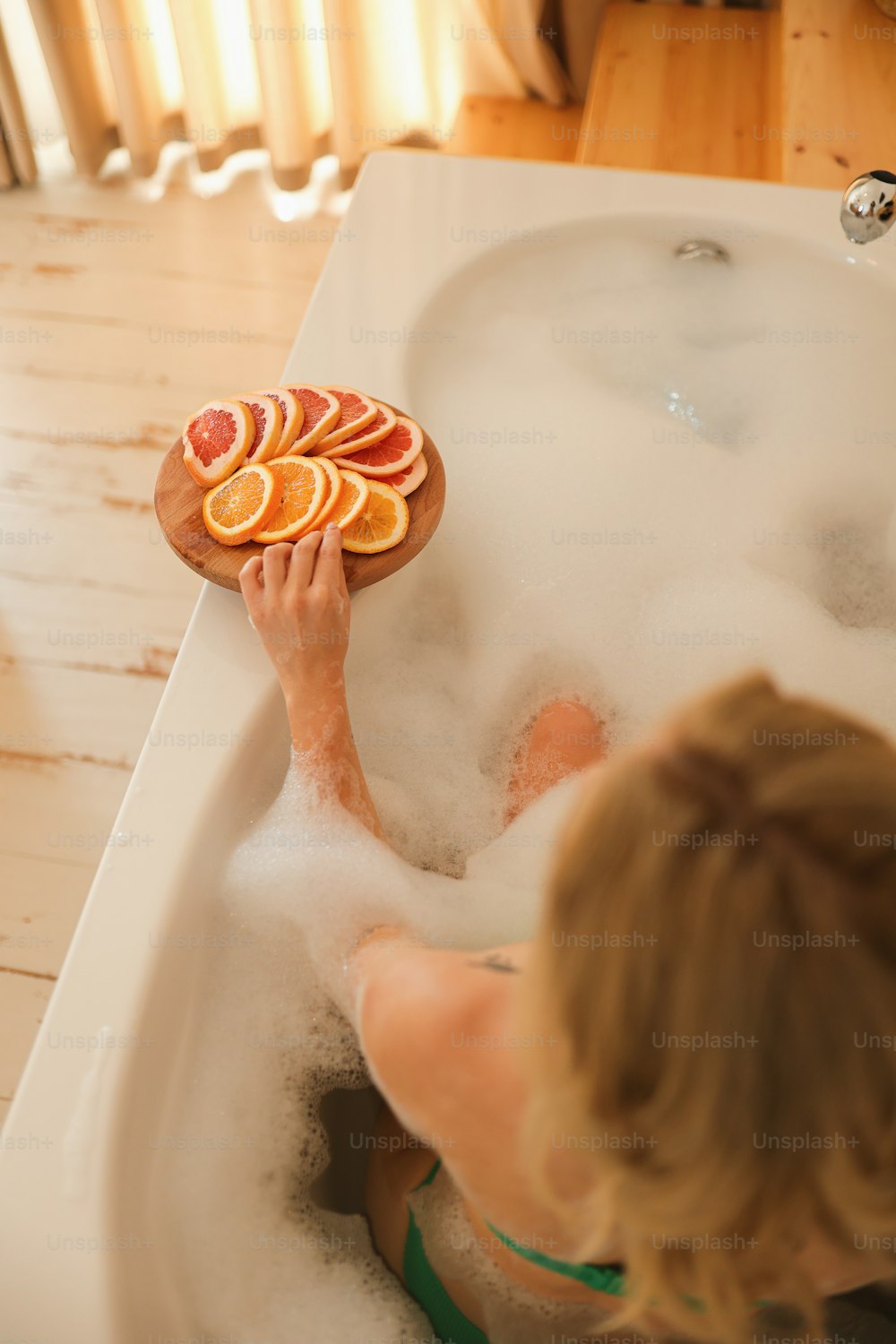 a woman sitting in a bathtub holding a pizza