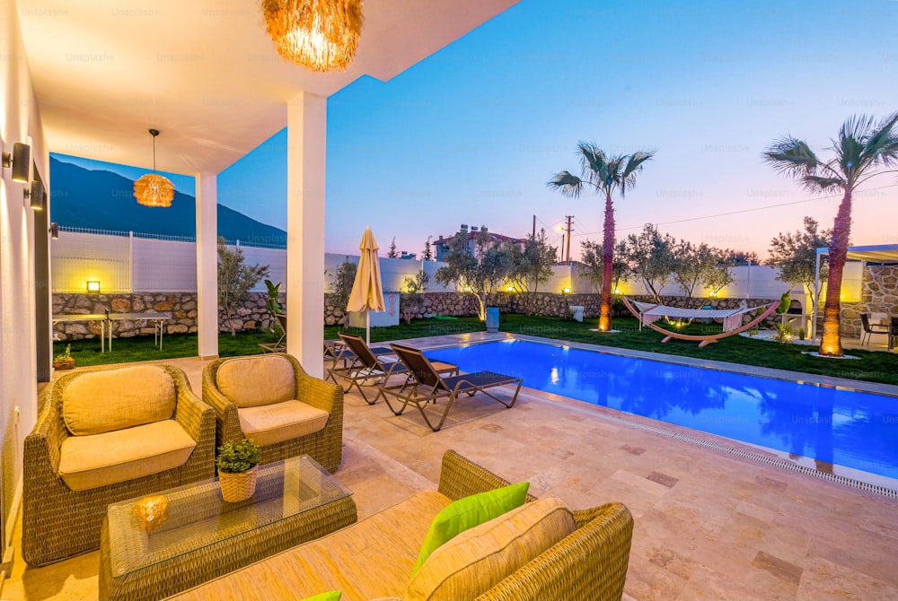 a backyard with a pool and patio furniture