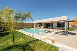 a backyard with a pool and lounge chairs