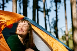 a woman sitting inside of a tent with her eyes closed