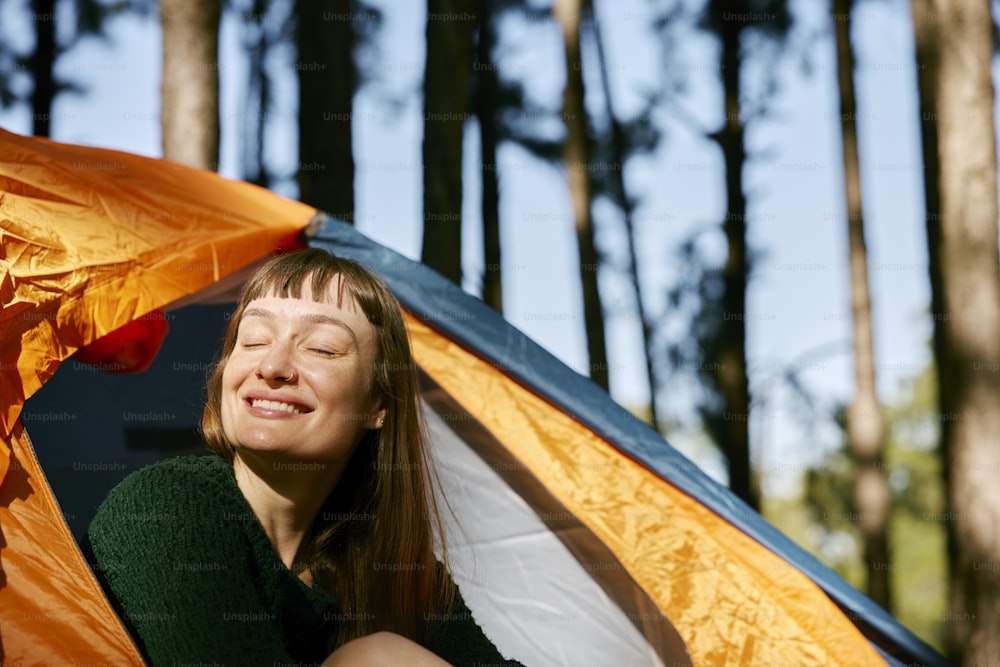 uma mulher sentada dentro de uma tenda com os olhos fechados