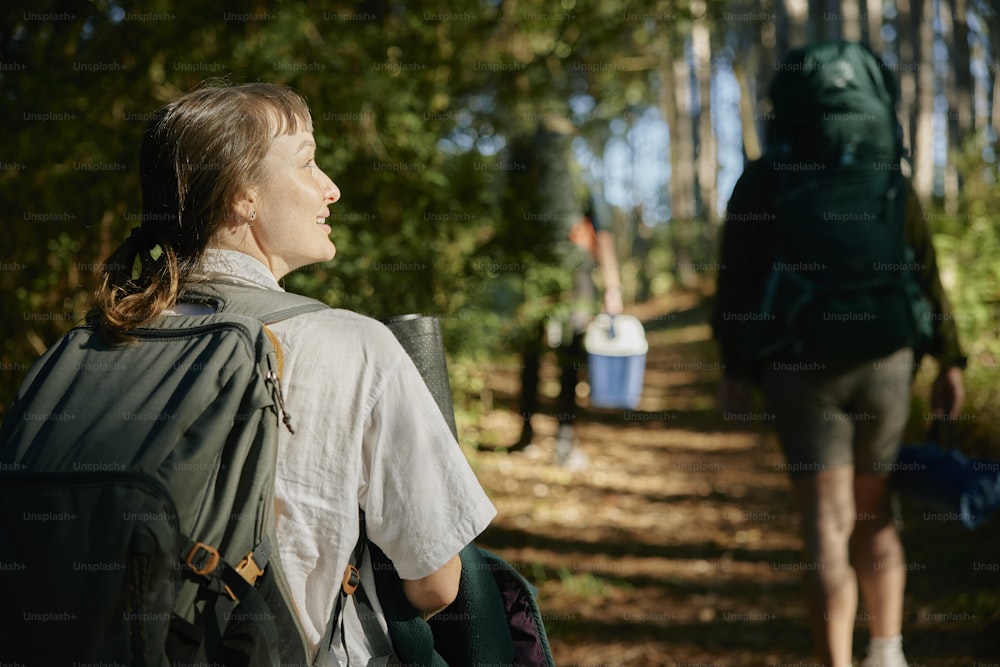 a woman with a backpack walking down a trail