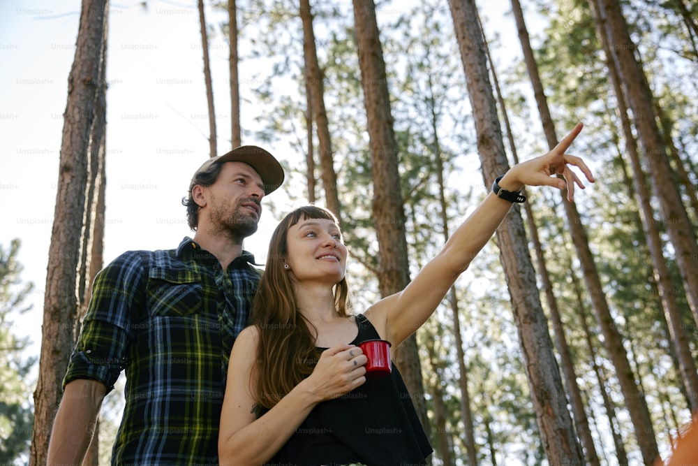 Ein Mann und eine Frau, die in einem Wald stehen und auf etwas zeigen