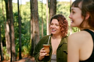 a woman standing next to another woman holding a drink