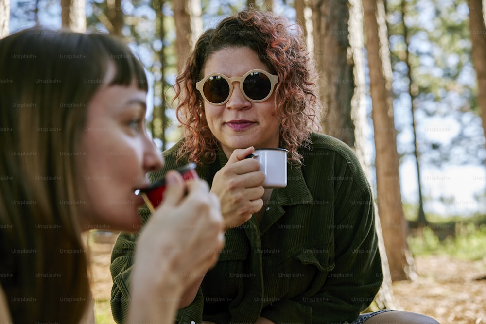 a woman in sunglasses is holding a cup