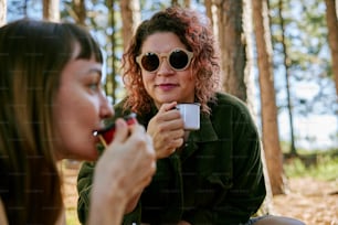 a woman in sunglasses is holding a cup