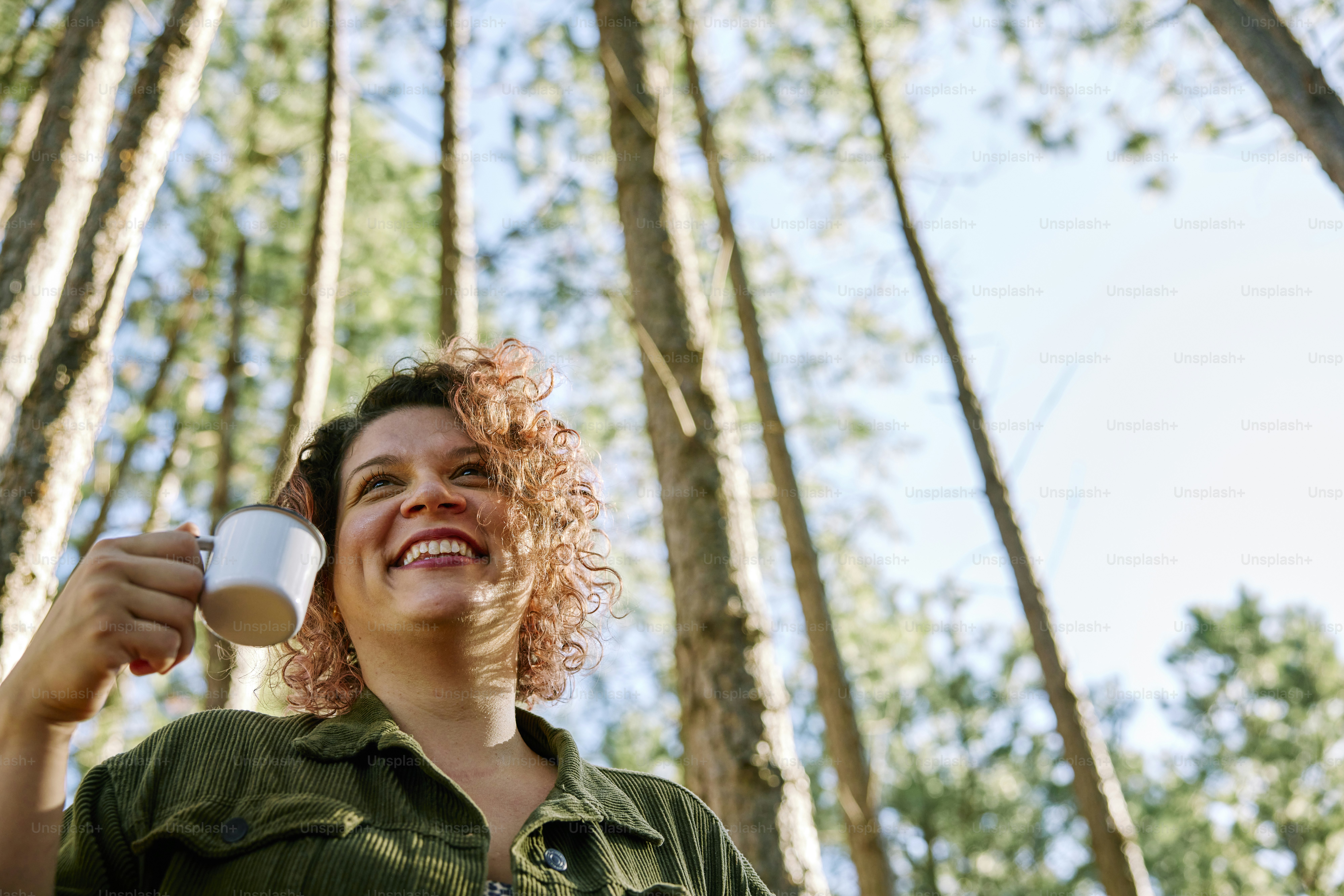 a woman holding a cup in a forest