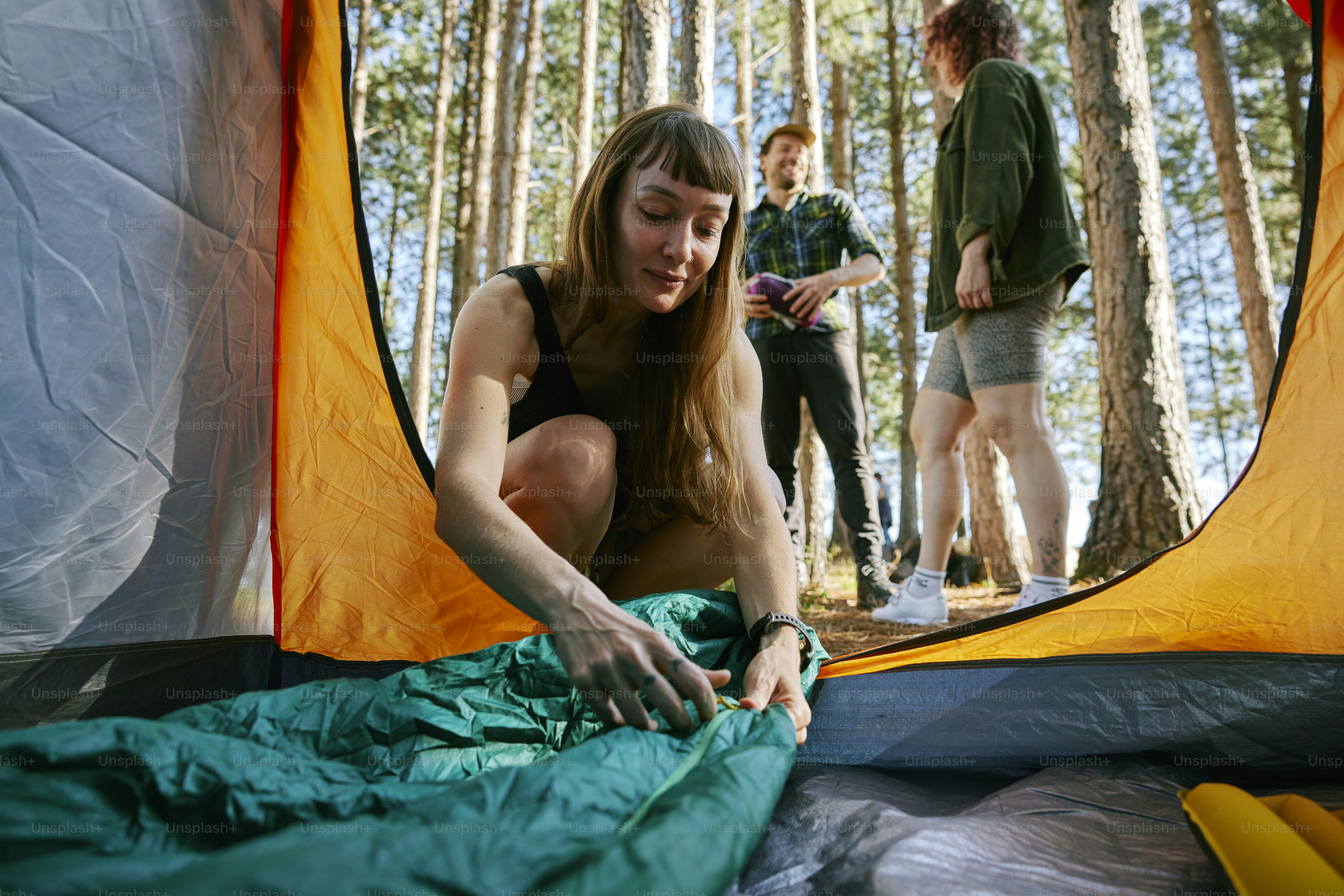 Camper inspecting smart camping gear problems beside a tent before sunset