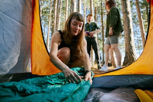 a woman is setting up a tent in the woods