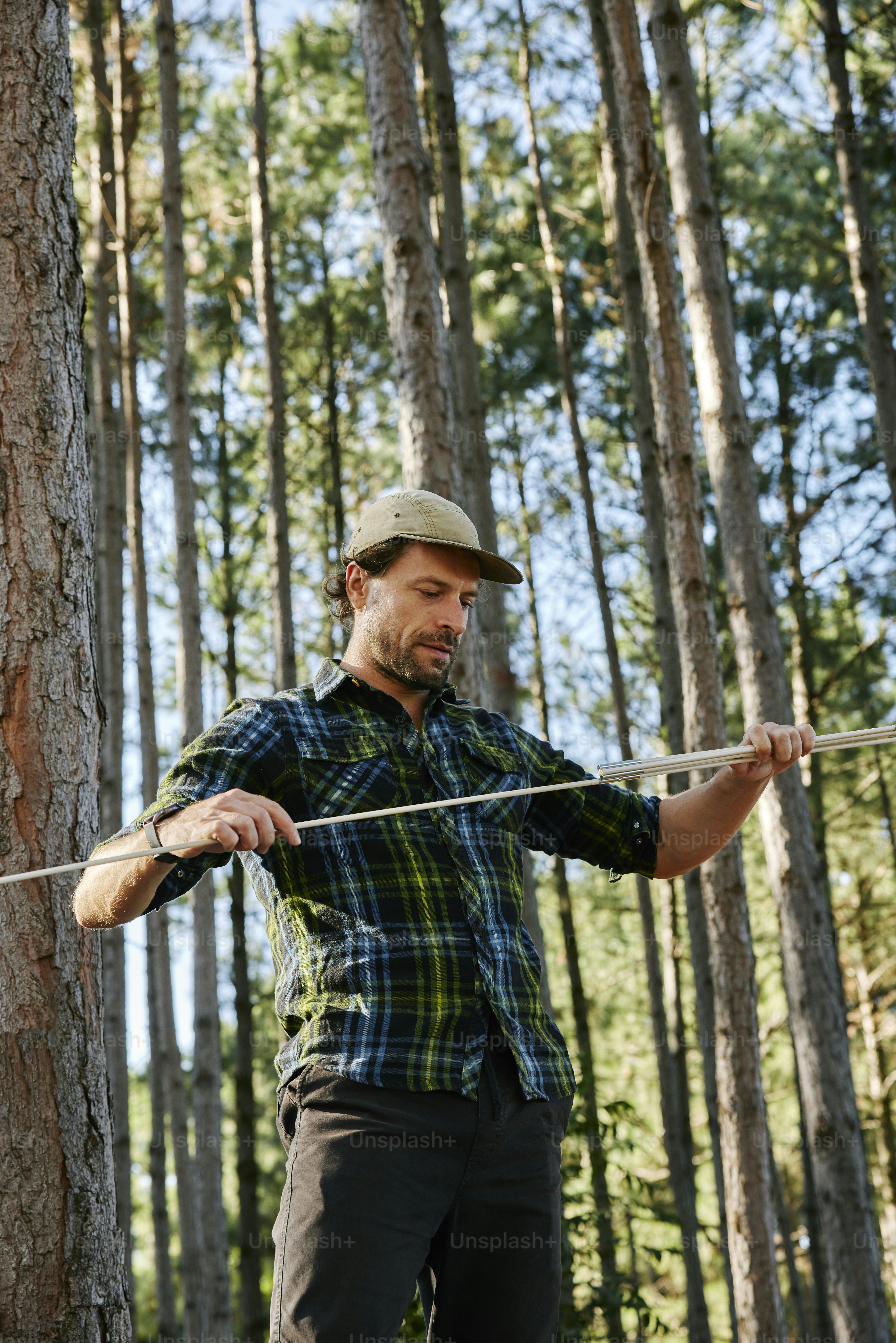 a man holding a stick in a forest