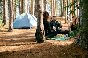 a group of people sitting on the ground in the woods