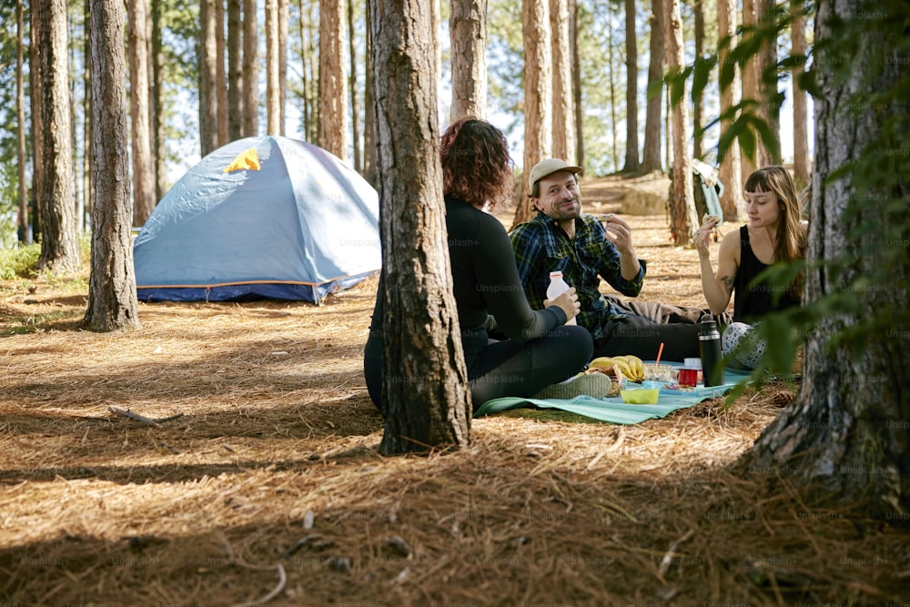 a group of people sitting on the ground in the woods