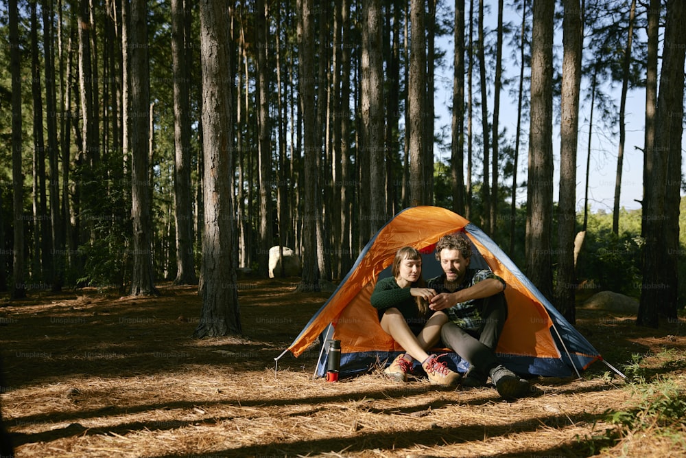 two people sitting in a tent in the woods