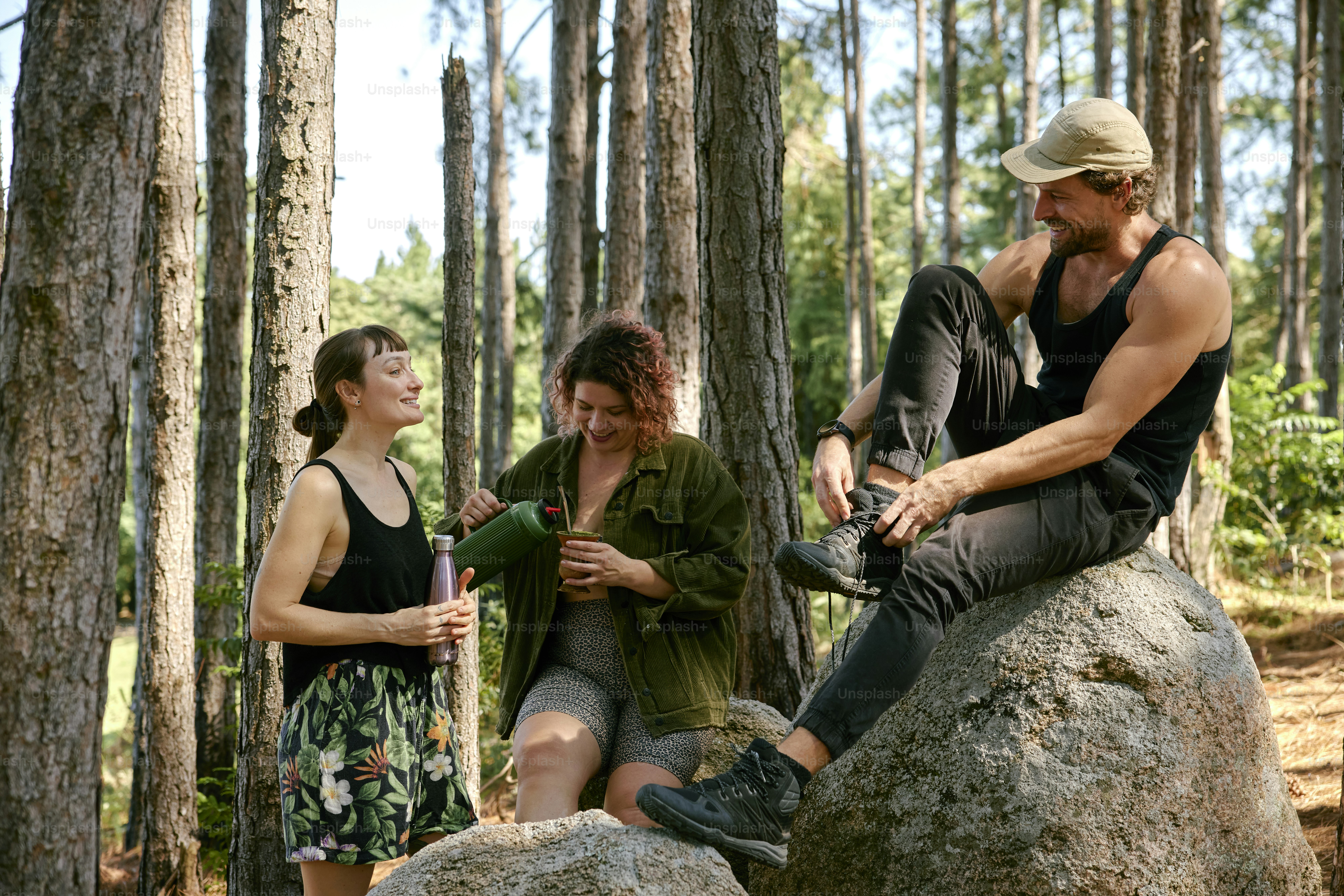 three people sitting on a rock in the woods