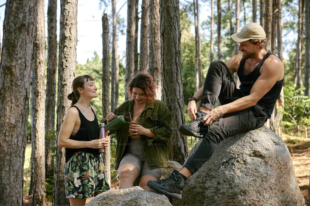 three people sitting on a rock in the woods