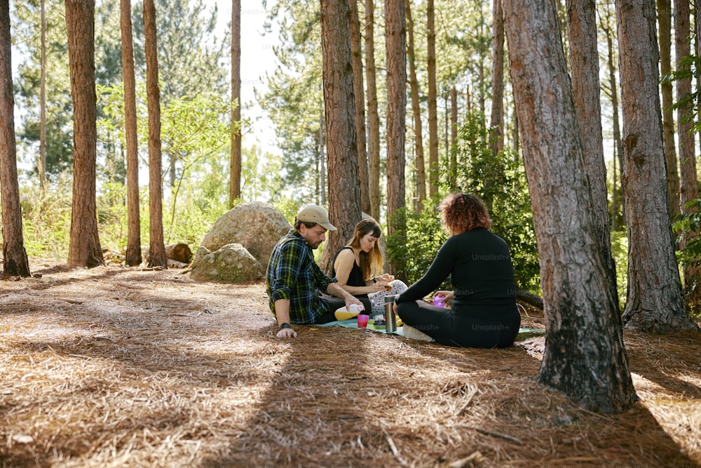 a man and a woman sitting on the ground in the woods