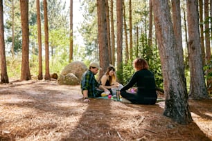 a man and a woman sitting on the ground in the woods