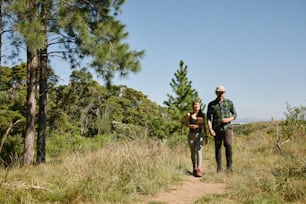 a man and a woman are walking through the woods