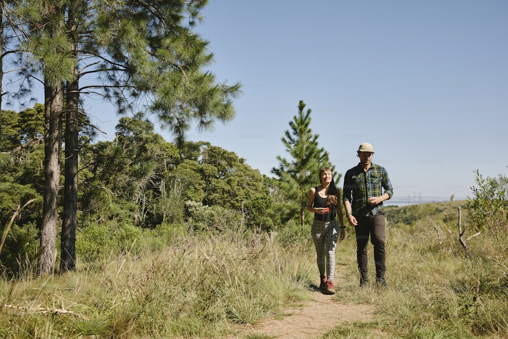um homem e uma mulher estão andando pela floresta