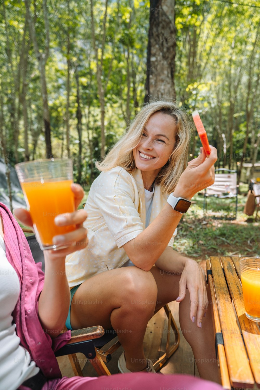 Une femme assise sur un banc tenant un verre de jus d’orange