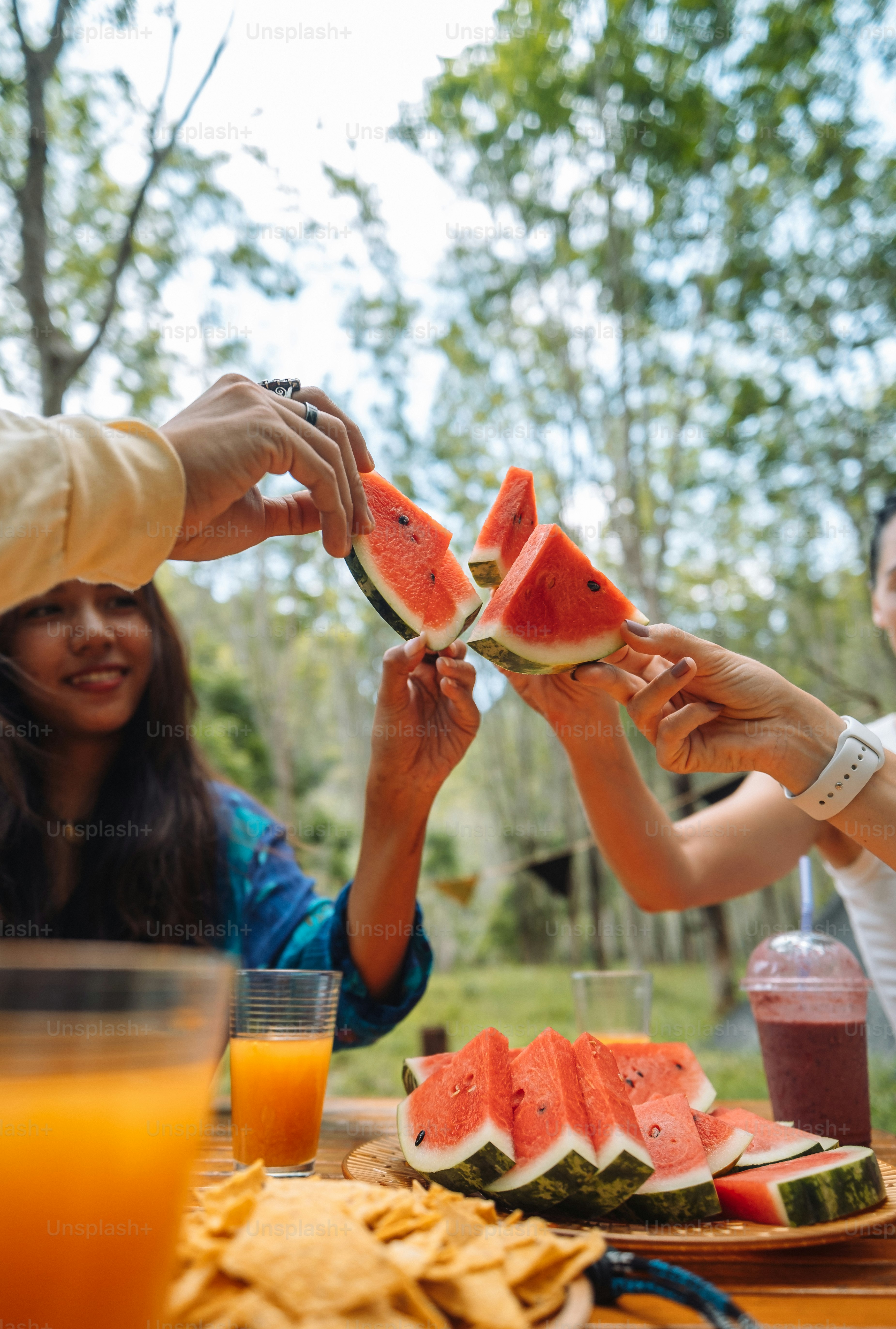 Un grupo de personas sentadas alrededor de una mesa comiendo sandía