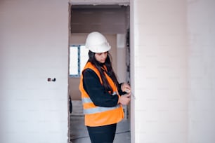 a woman in a hard hat and safety vest looking at a cell phone