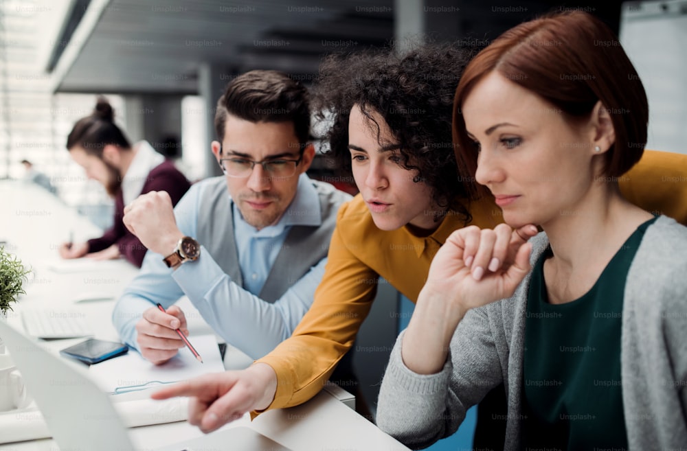 A group of young businesspeople working together in office, talking.