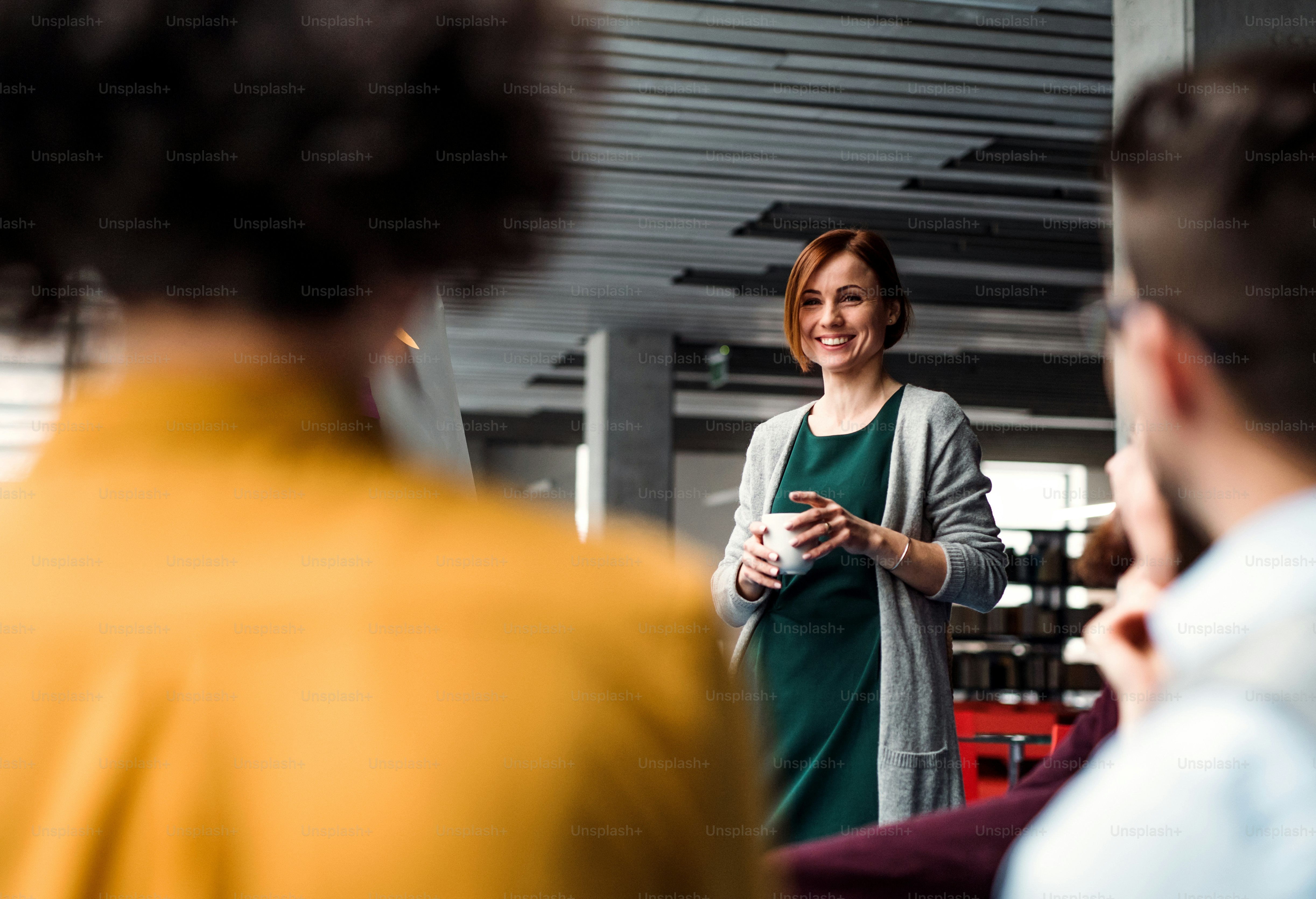 A group of young businesspeople listening to a presentation in office, talking.