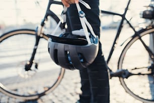 Section médiane d’un banlieusard méconnaissable avec vélo électrique et casque voyageant en ville.