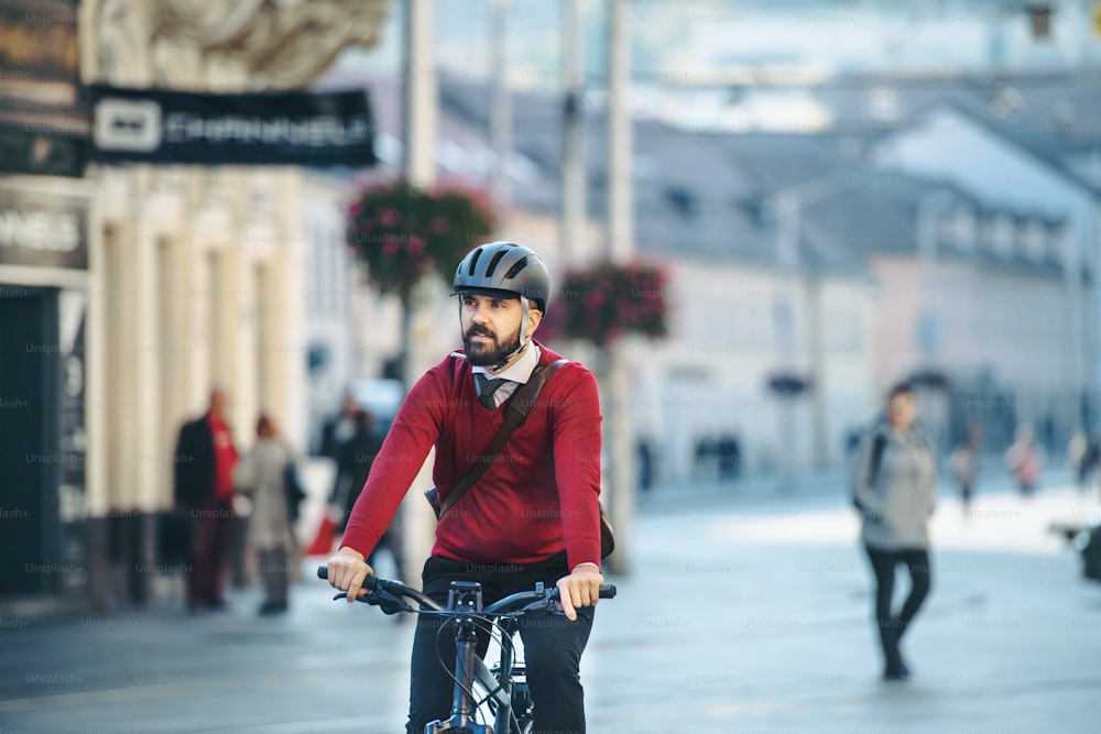 Pendolare uomo d'affari hipster con bicicletta elettrica che viaggia per lavorare in città. Copia spazio.