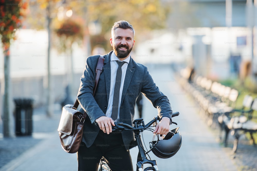 A businessman commuter with bicycle walking home from work in city.