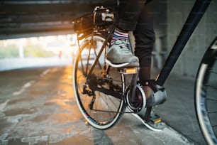 Sezione centrale di pendolare uomo d'affari irriconoscibile con bicicletta elettrica che viaggia dal lavoro in città. Copia spazio.