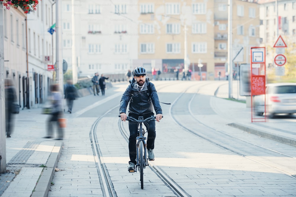 Pendolare uomo d'affari hipster con bicicletta elettrica che torna a casa dal lavoro in città al tramonto. Copia spazio.