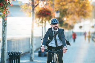 Homme d’affaires hipster avec vélo électrique rentrant du travail en ville au coucher du soleil. Espace de copie.