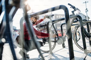 Un hombre de negocios hipster que estaciona bicicletas eléctricas en la ciudad cuando va a trabajar.
