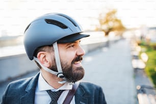 Hipster businessman commuter with a bicycle helmet traveling home from work in city. Copy space.