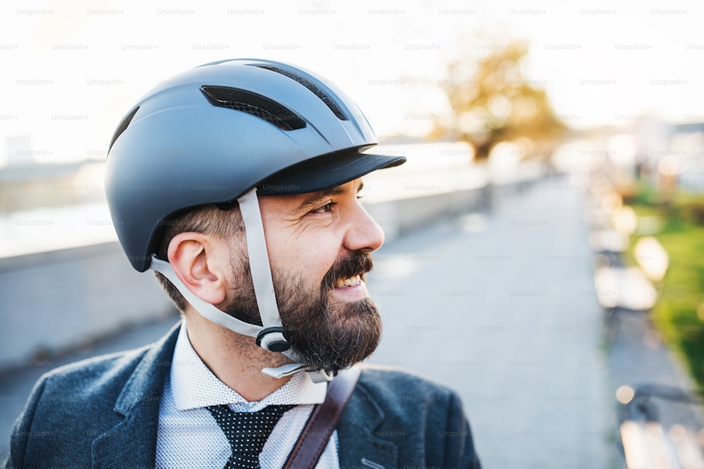 Hipster businessman commuter with a bicycle helmet traveling home from work in city. Copy space.