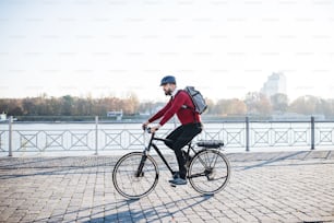 市内で働くために旅行する電動自転車を持つ流行に敏感なビジネスマンの通勤者の側面図。スペースをコピーします。