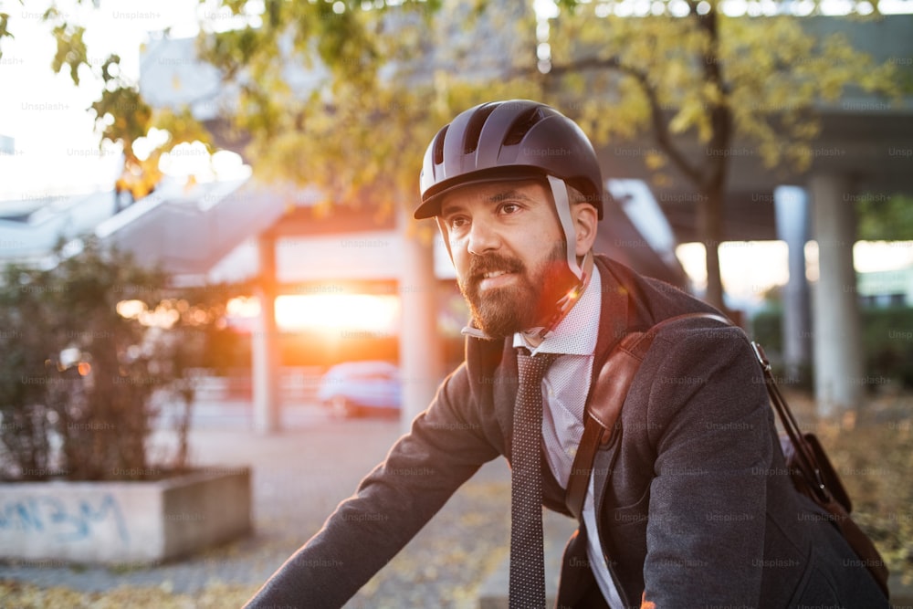 Hipster businessman commuter with bicycle traveling home from work in city at sunset. Copy space.