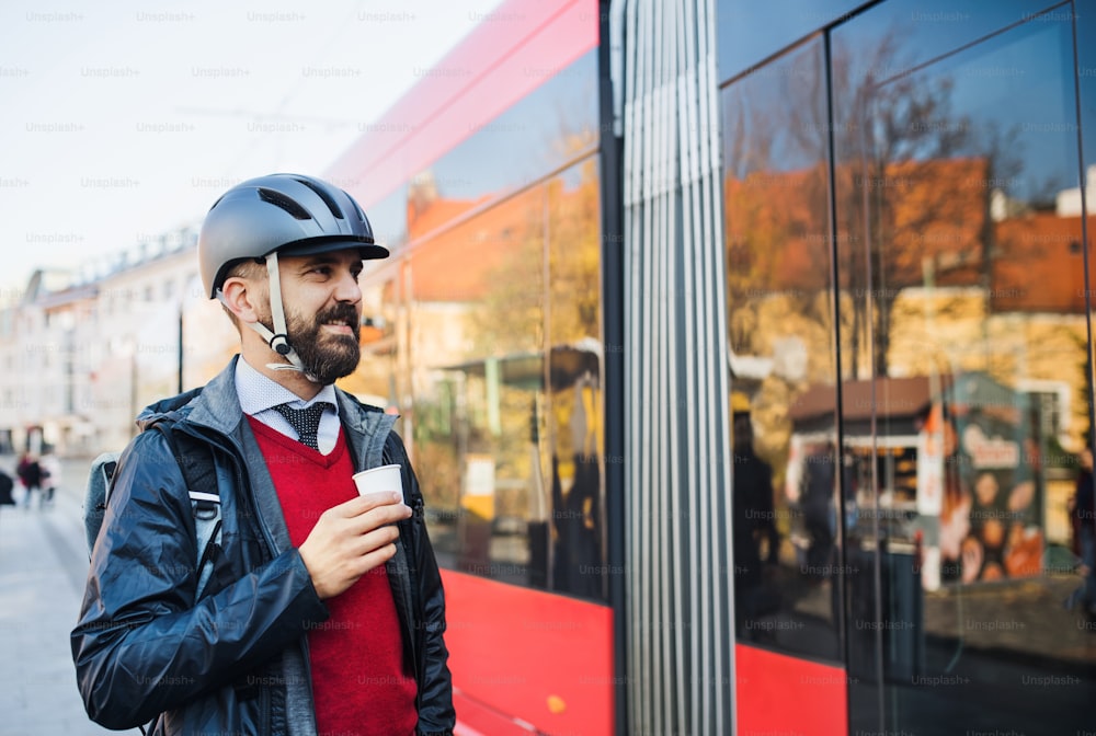 Businessman commuter with bicycle helmet going home from work in city.