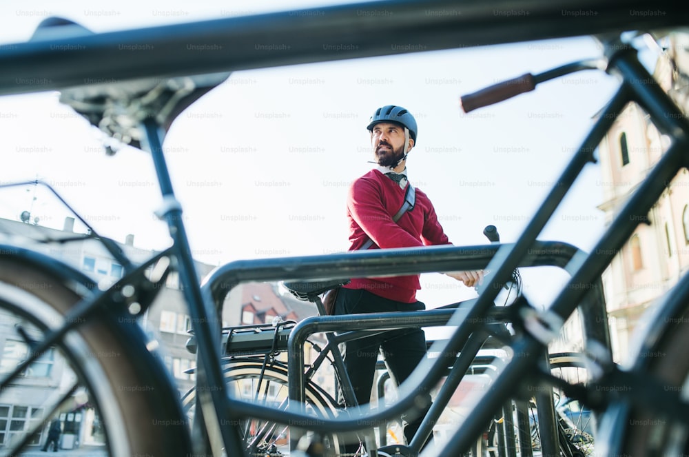 Ein Hipster-Geschäftsmann, Pendler, der Elektrofahrräder in der Stadt parkt, wenn er zur Arbeit geht.